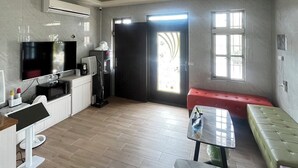 A modern living room with a flat-screen TV, a coffee machine, and a dining area with a table and benches. - Overseas Ryukyu studies Homestay (Liuqiu)