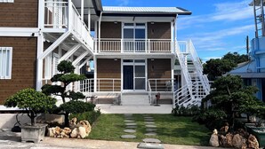 A two-story building with a balcony, a staircase, and a small garden area with rocks and plants. - Overseas Ryukyu studies Homestay (Liuqiu)
