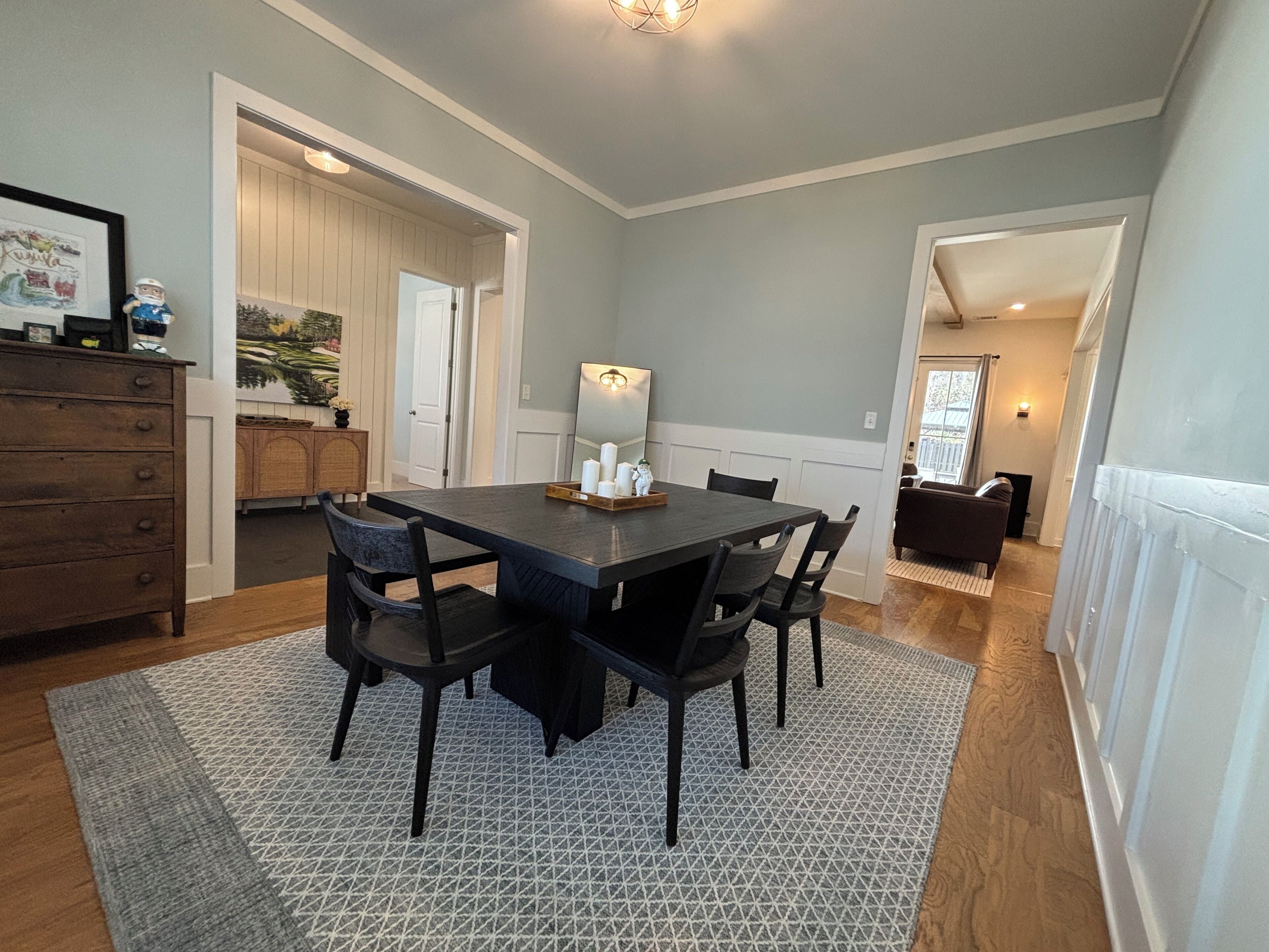 Un coin repas avec une table et des chaises en bois foncé, un tapis à motifs et un luminaire suspendu au-dessus de la table.