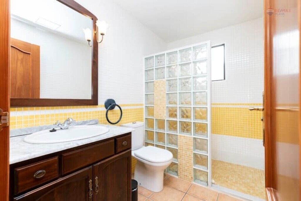Ein Badezimmer mit einem weißen Waschbecken, einem Holz-Waschtisch und einer Toilette.