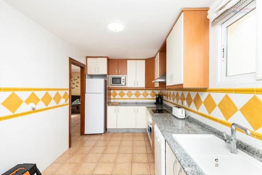 A compact kitchen with white and wooden cabinets, a microwave, and a sink.