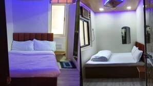 Hotellihuone, jossa on sänky, ikkuna, peili ja kattotuuletin.