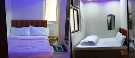 A hotel room with a bed, a window, a mirror, and a ceiling fan.