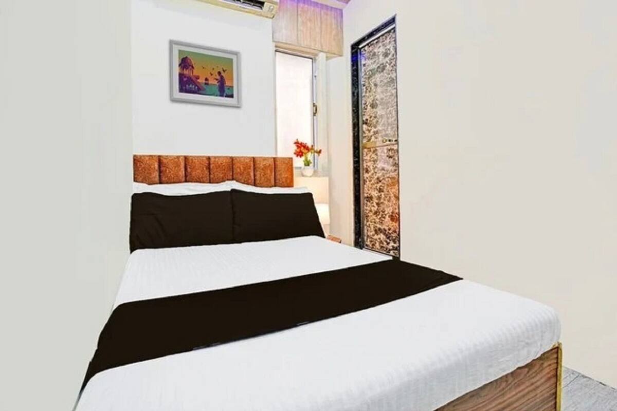 Una cama bien tendida con una colcha blanco y negra, un cabecero de madera y un cuadro en la pared.