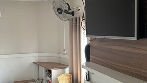 A compact kitchen with a dining area, a TV mounted on the wall, and a ceiling fan. - Hotel Hallas (Betim)
