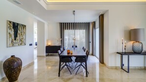 A modern dining area with a long table, chairs, a vase, and a lamp. - Luxury Family Villa for in Marbella (Marbella)