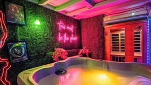 Ett spaområde med ett bubbelbad, neonljus och en grön vägg.