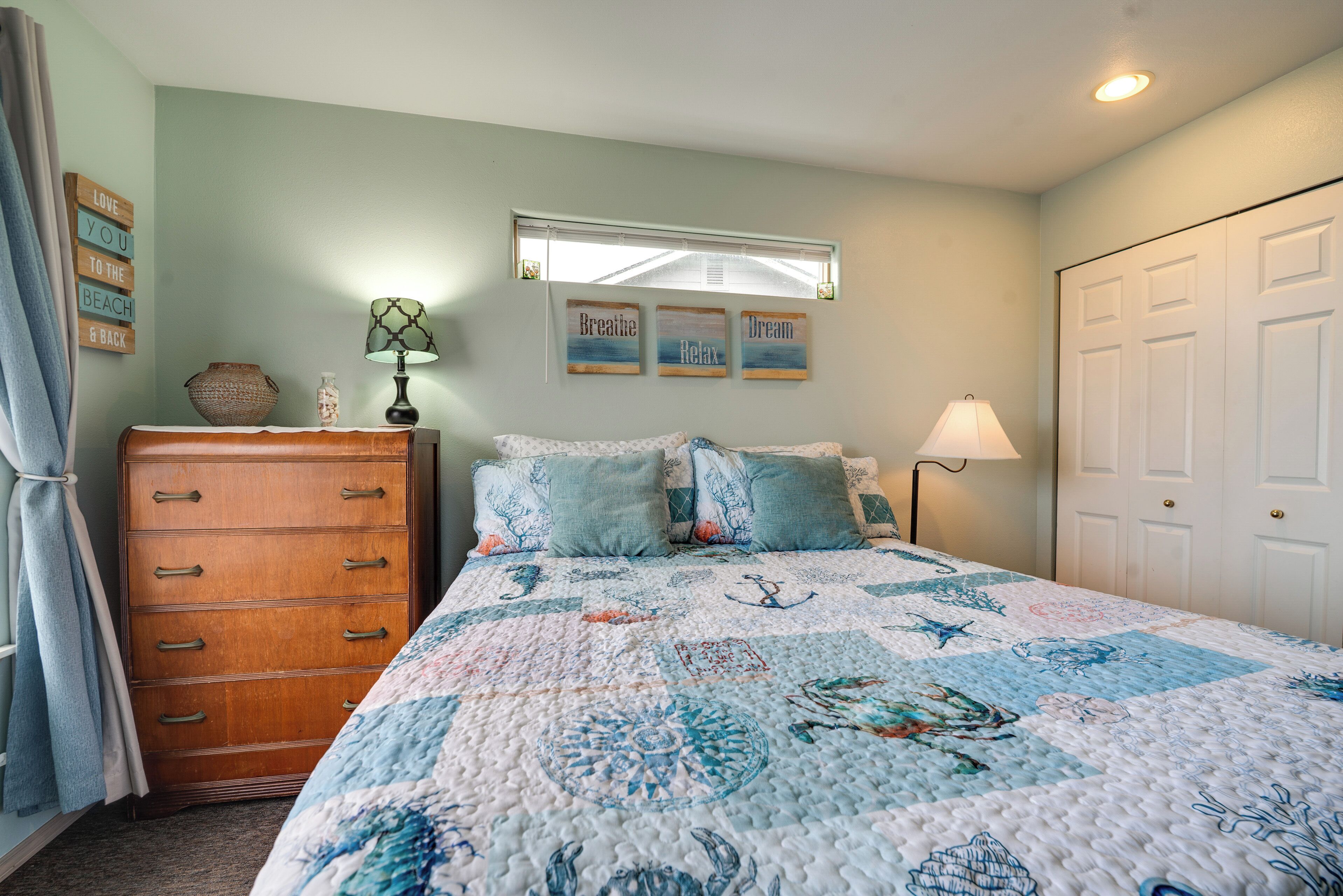 A bedroom with a bed, dresser, and wall decorations.