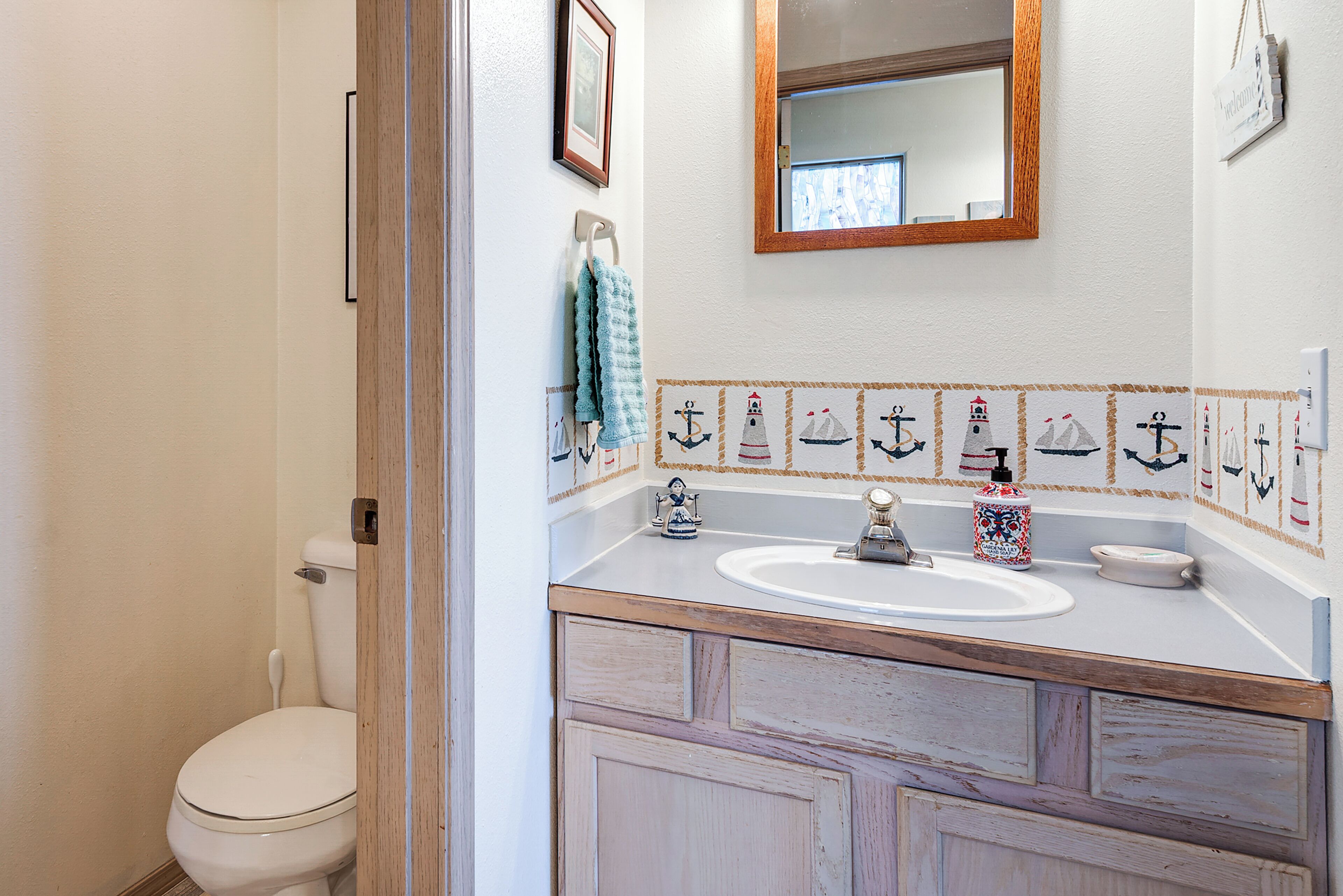 Une salle de bain avec des toilettes blanches, un meuble-lavabo en bois et un miroir.