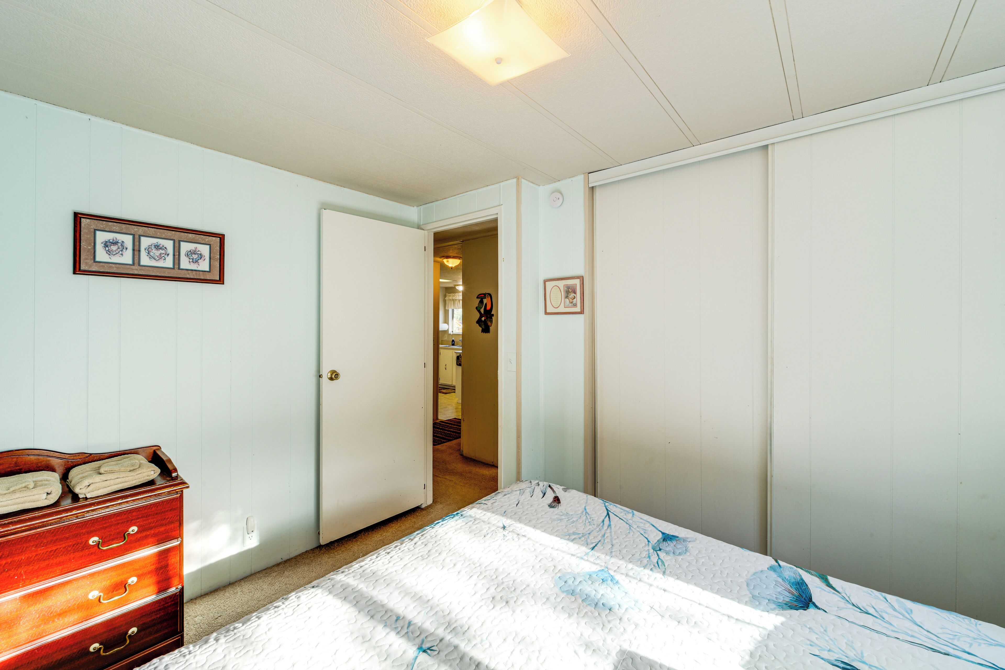 Un dormitorio con cama, cómoda y puerta que da a otra habitación.