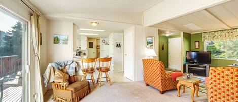 A spacious living room with a sofa, chairs, a television, and a dining area.
