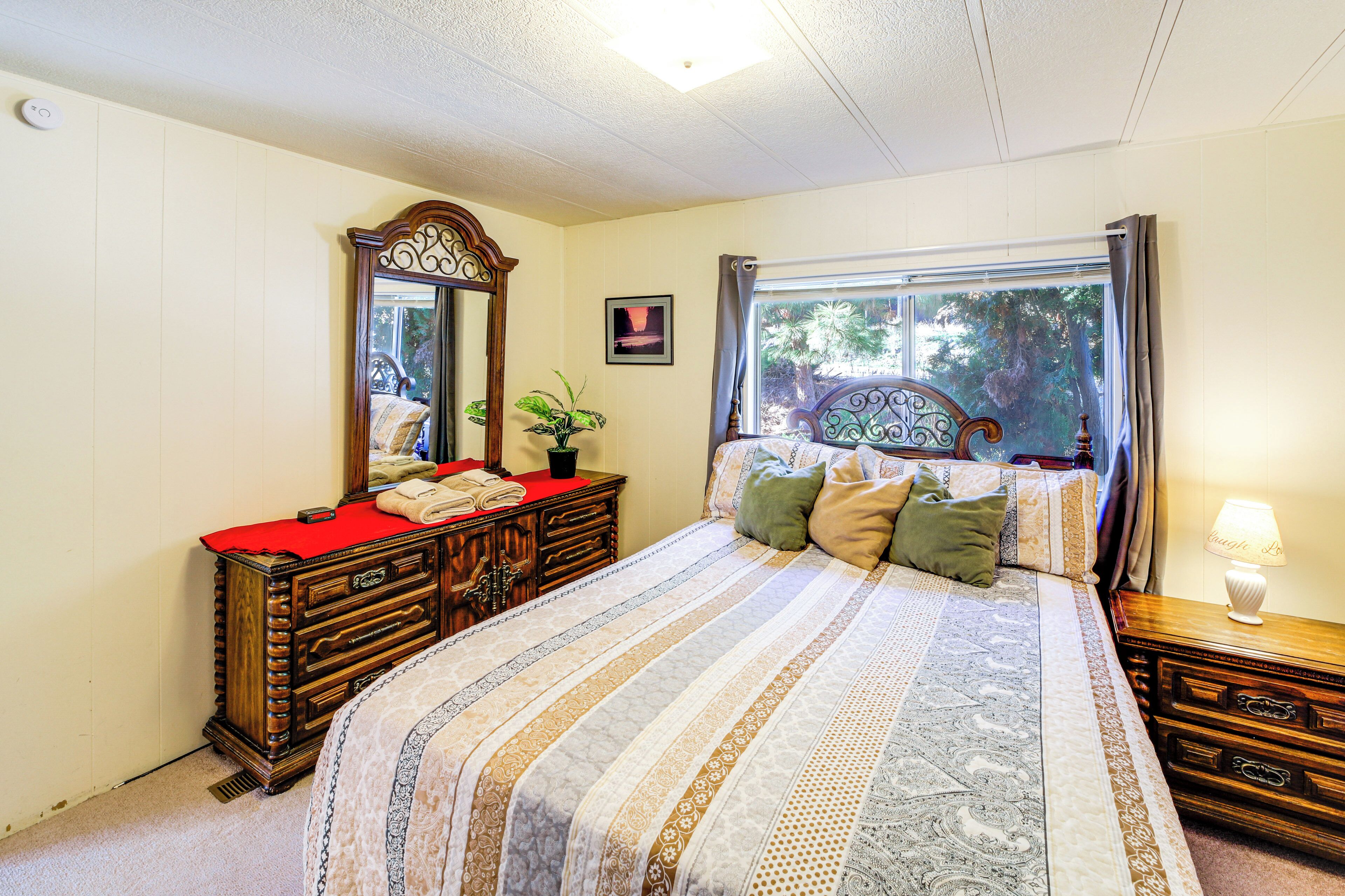 Un dormitorio con una cama grande, un aparador, un espejo y una ventana con cortinas.