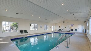 Een binnenzwembad met helderblauw water, een badmeesterstation en een bord met daarop dat er geen badmeester aanwezig is.