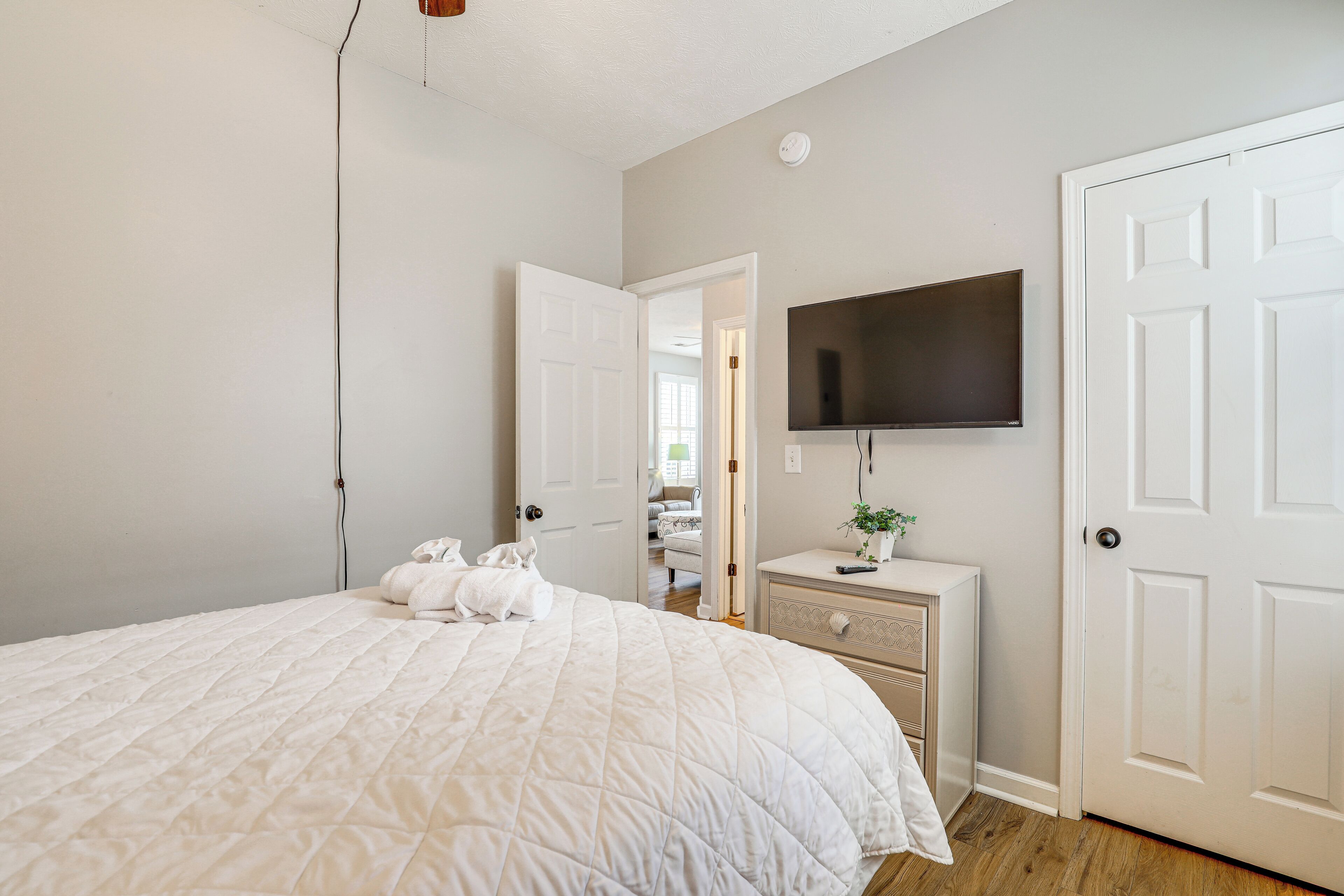 Een slaapkamer met een groot bed, een dressoir, een televisie en een deur.