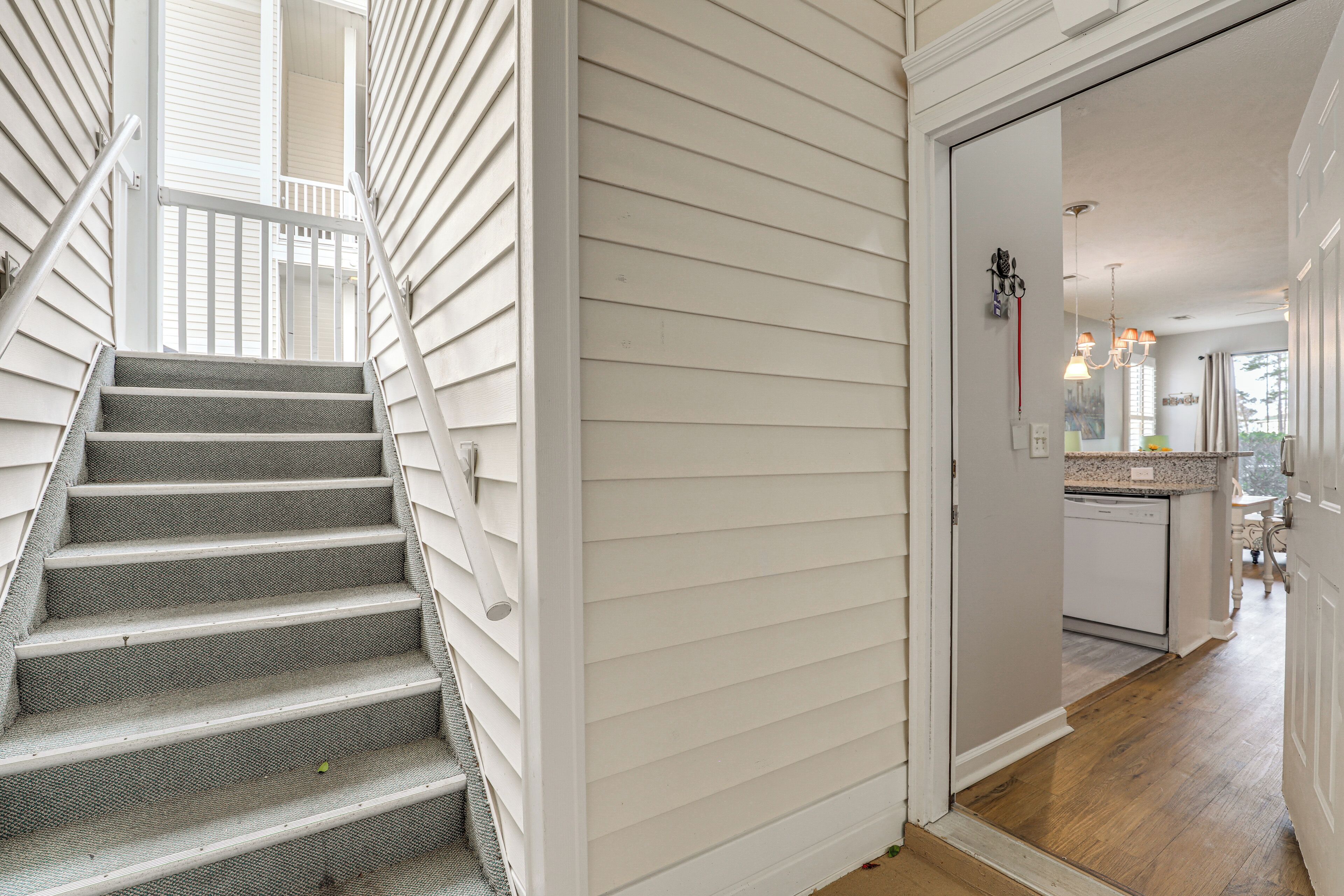 A staircase leading to a second floor with white siding and a kitchen area visible in the background.