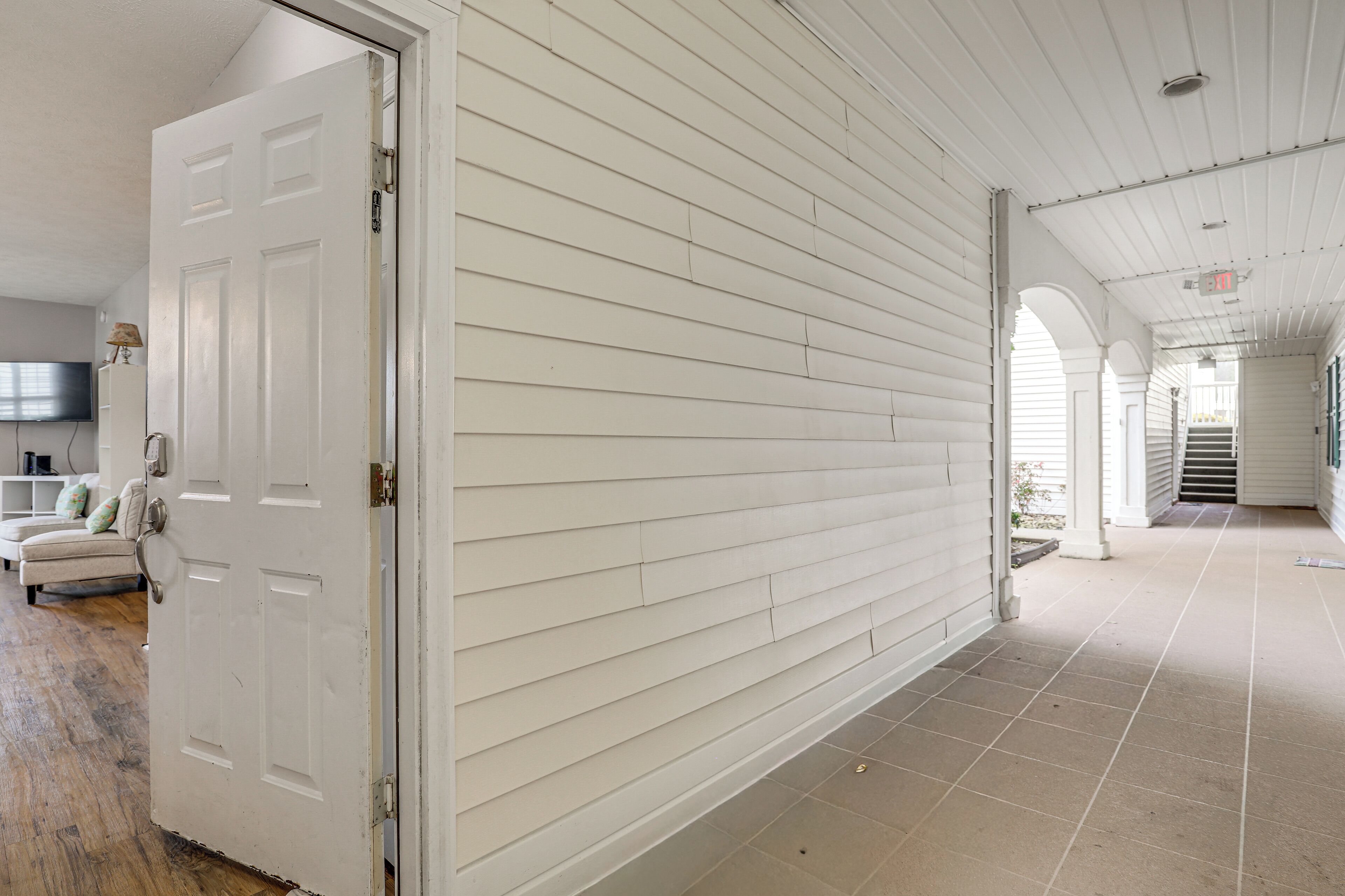 A corridor with white siding walls and a tiled floor.