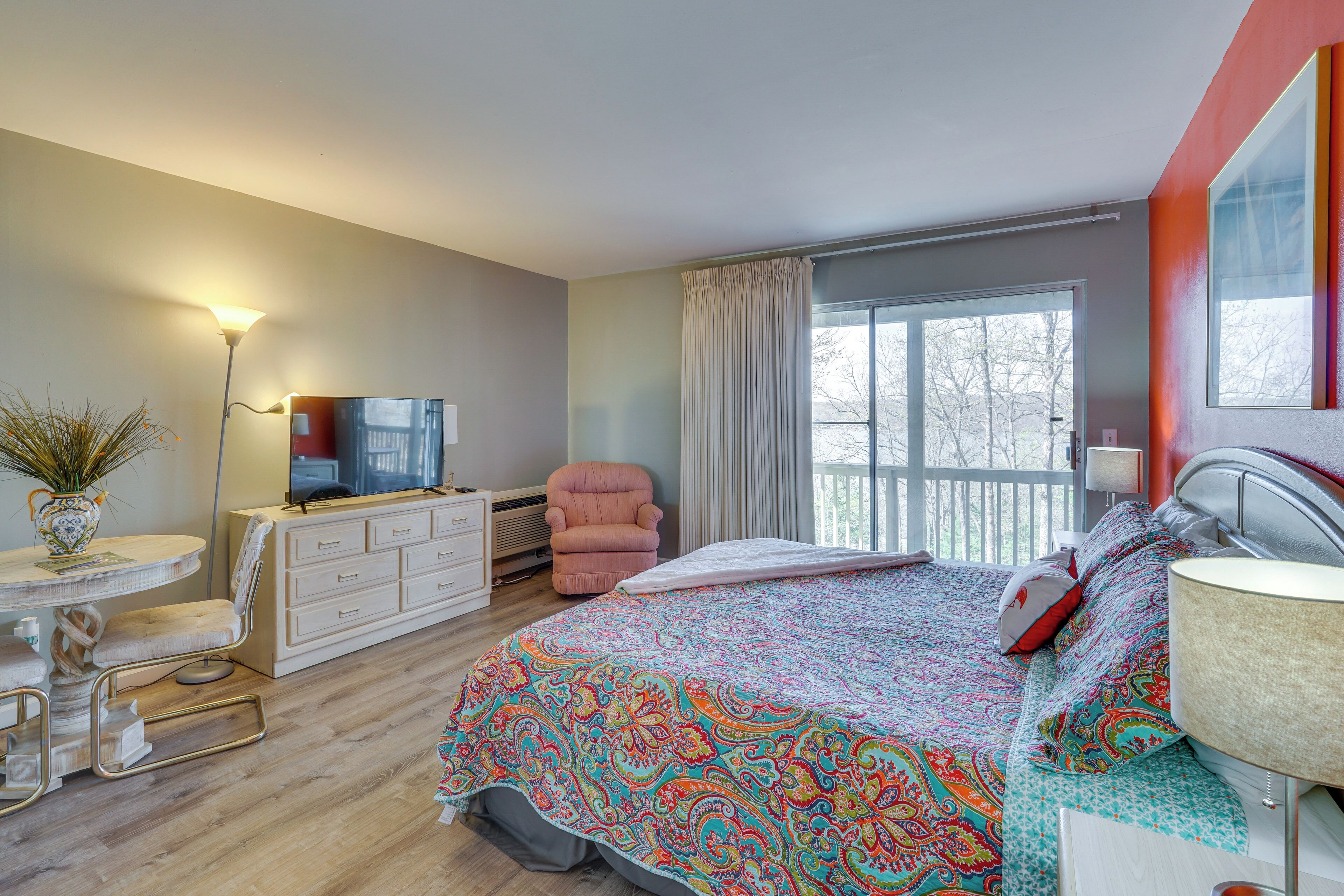 Une chambre à coucher avec un lit, une télévision, une chaise, une commode et une fenêtre avec des rideaux.