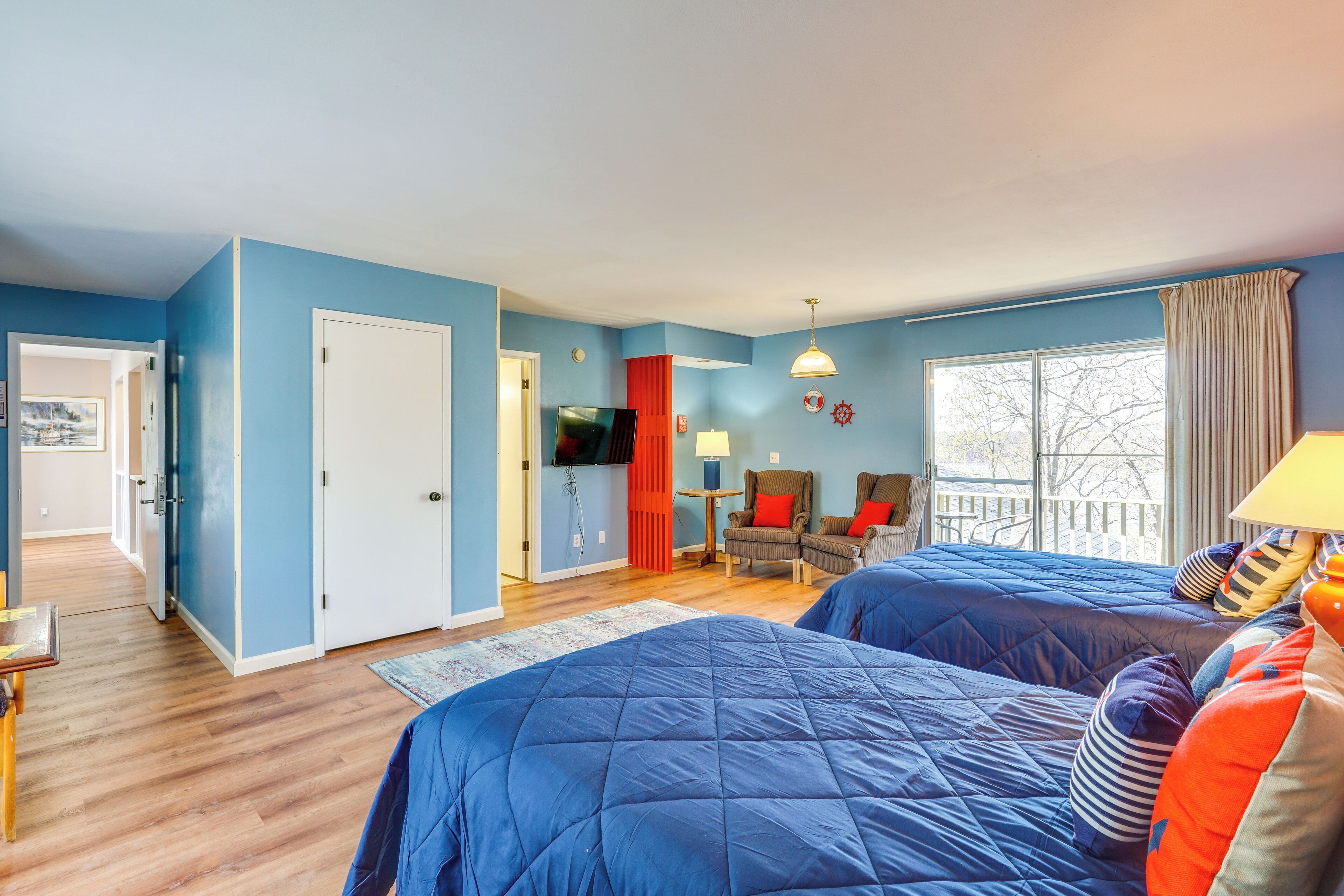Une chambre avec deux lits, une télévision, un bureau et une fenêtre avec des rideaux.