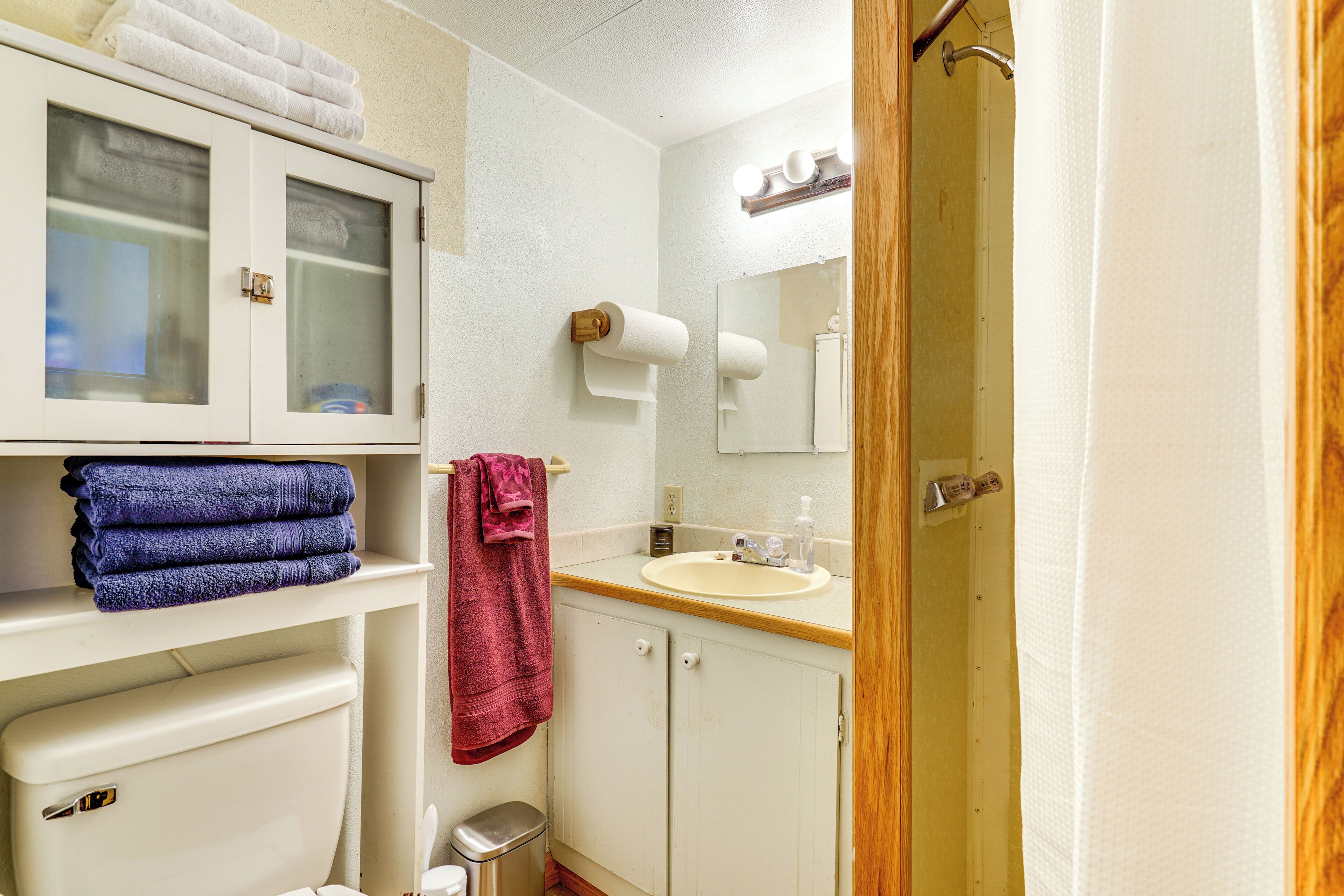 A bathroom with a toilet, sink, mirror, and towel rack.