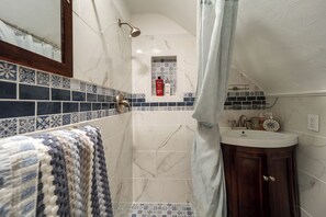 A bathroom with a shower, a sink, and a towel rack.