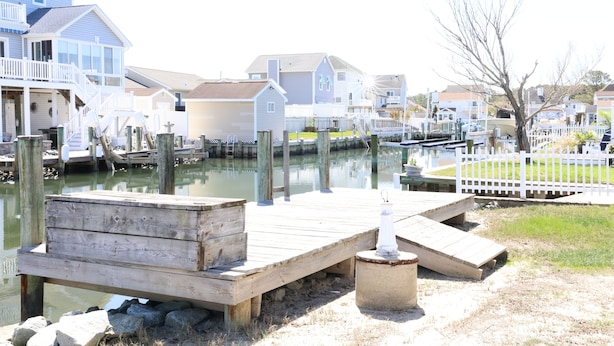 A waterfront property with wooden docks, a small pier, and a white fence. - West Ocean City Vacation House Rental in Quiet Residential Neighborhood (Ocean City)