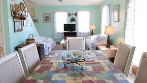 A cozy living room with a quilted table, a television, and various decorative items. - West Ocean City Vacation House Rental in Quiet Residential Neighborhood (Ocean City)