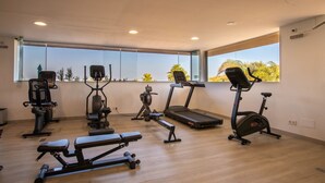 Un gimnàs modern amb diversos equips d'exercici, grans finestres i un sòl de fusta.