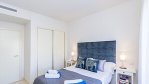 Habitació d'hotel amb un llit, dues taules de nit, un armari i una estantària amb llibres.