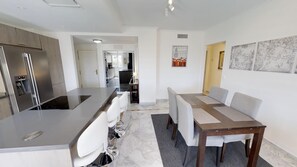 A modern kitchen with stainless steel appliances, a central island with seating, and a dining area with a table and chairs. - Modern Sea-side Apartment for 6 (Marbella)