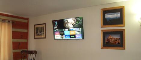 Camera d'albergo con un letto, una televisione a muro che mostra diversi servizi di streaming e due quadri appesi.