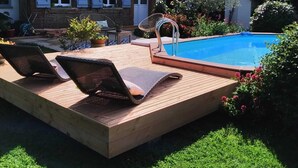 Une maison à deux étages dotée d’une piscine, d’une terrasse en bois et d’un espace salon extérieur.
