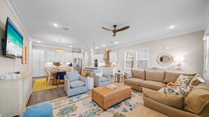 A modern living room with a sofa, ottoman, and a dining area with chairs and a table. - New! 5 minutes from Rosemary Beach! Bikes, Beach Gear, Game & Bunk Room, 8 Beds (Inlet beach)