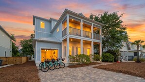 A two-story house with a covered porch, a garage, and a driveway. - New! 5 minutes from Rosemary Beach! Bikes, Beach Gear, Game & Bunk Room, 8 Beds (Inlet beach)