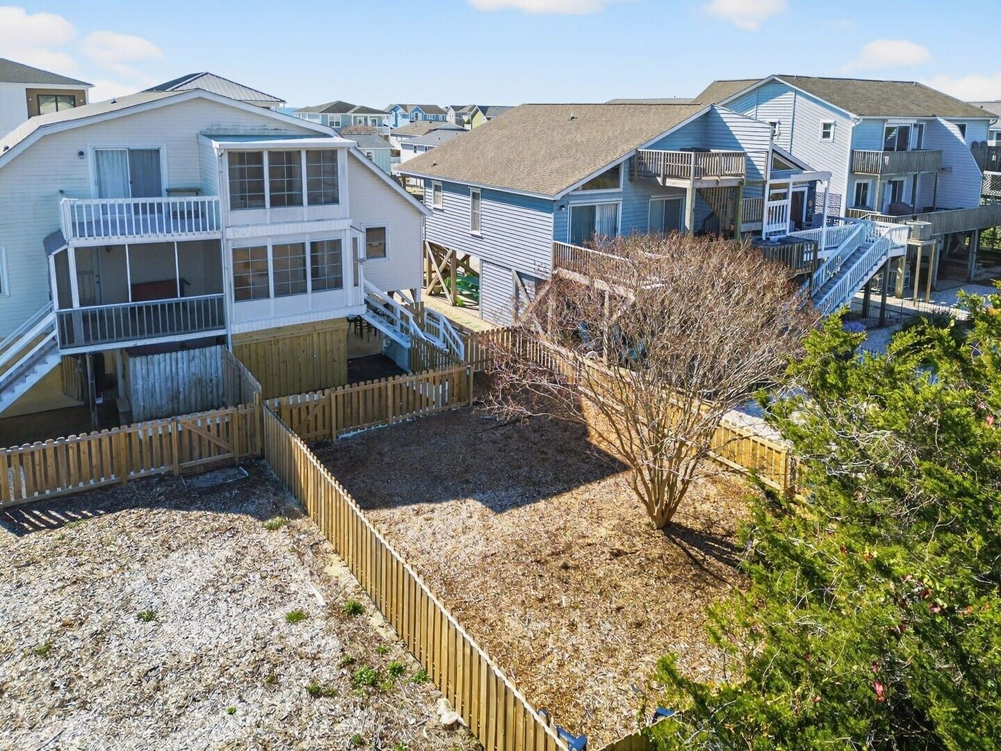 A coastal residential area with multiple two-story houses featuring balconies and wooden fences.