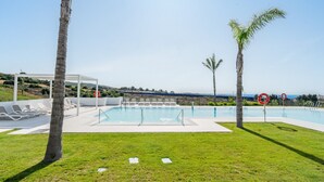 A pool area with lounge chairs, a pergola, and palm trees. - Alcazaba Lagoon Retreat for 4 (Casares)