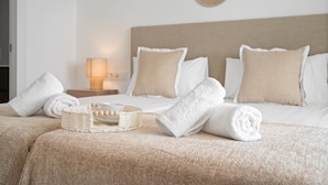 A neatly made bed with white and beige bedding, a bedside lamp, and a woven basket with wooden balls. - Alcazaba Lagoon Retreat for 4 (Casares)