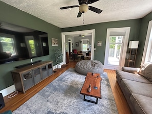 A living room with a ceiling fan, a bean bag, a coffee table, a sofa, and a television.