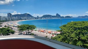 A coastal cityscape with a beach, buildings, and a prominent mountain. - Atlantic Avenue, Post 6, Incredible View  (Rio de Janeiro)