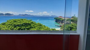 A coastal view from a window overlooking a beach with a pier, a bridge, and distant mountains. - Atlantic Avenue, Post 6, Incredible View  (Rio de Janeiro)