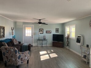A living room with a ceiling fan, a TV, a small table, and a sofa. - Cabin with Saluda River access (Honea Path)