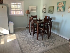 A dining area with a table and chairs, a lamp, a trash can, and artwork on the walls. - Cabin with Saluda River access (Honea Path)
