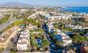 An aerial view of a coastal residential area with white buildings, a road, and a large body of water. - Beachside Penthouse With Rooftop Terrace (Estepona)