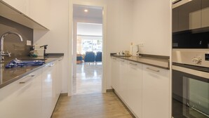 A modern kitchen with white cabinets, stainless steel appliances, and a wooden floor. - Beachside Penthouse With Rooftop Terrace (Estepona)