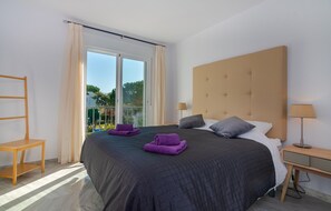 A modern hotel room with a large bed, a wooden nightstand, a chair, and a view of greenery through the window. - Beachside Penthouse With Rooftop Terrace (Estepona)