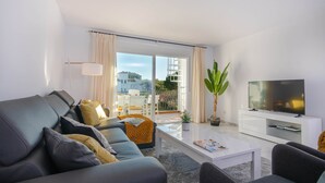 A modern living room with a sofa, coffee table, TV, and a balcony with outdoor furniture. - Beachside Penthouse With Rooftop Terrace (Estepona)