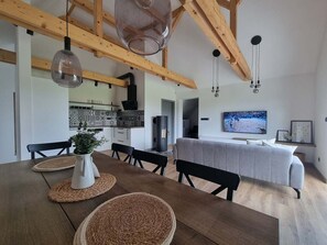 Uma área de refeições com uma mesa de madeira, jogos americanos trançados e um vaso branco com flores.