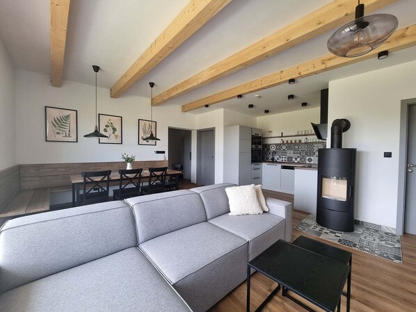 Una sala de estar moderna con un sofá seccional gris, una mesa de centro negra y un estufa de leña.