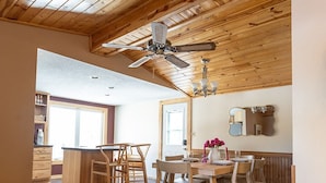 Una cocina amplia con armarios de madera, una isla central y un comedor con sillas y mesa de madera.