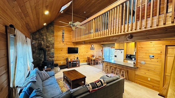 Interior de una cabaña de troncos con sala de estar, cocina y balcón.