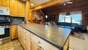 Una cocina con armarios de madera, encimera de granito, microondas y estufa.